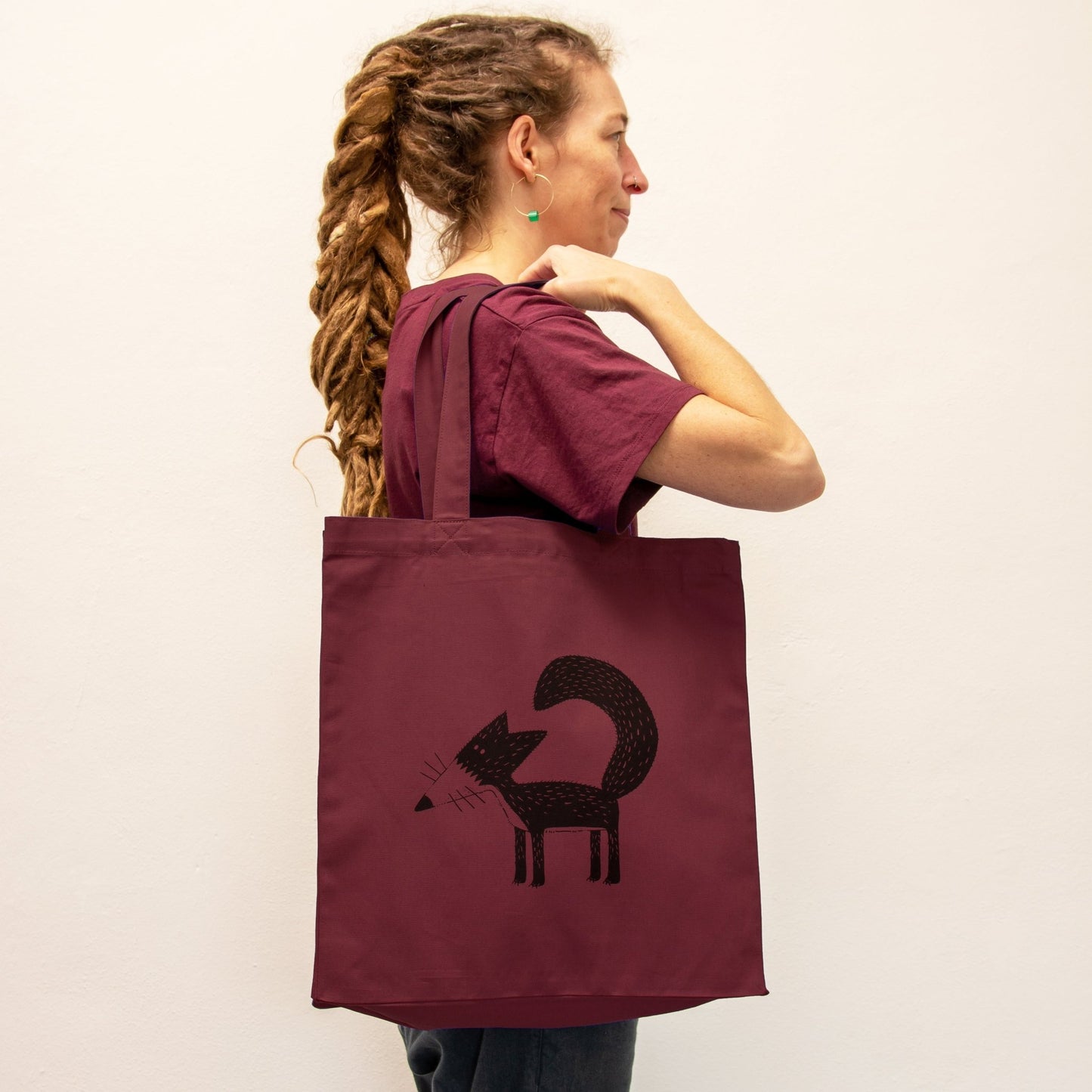 Fuchs Jutebeutel in Burgundy getragen von einer Frau. Der weinrote Shopper mit Tiermotiv zeigt sich als stilvoller Alltagsbegleiter und kreatives Geschenk für Frauen.