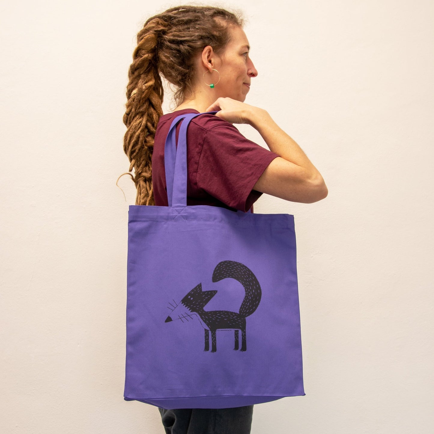 Fuchs Jutebeutel in Purple getragen von einer Frau. Der violette Shopper mit Tiermotiv zeigt sich als stilvoller Alltagsbegleiter und kreatives Geschenk für Frauen.