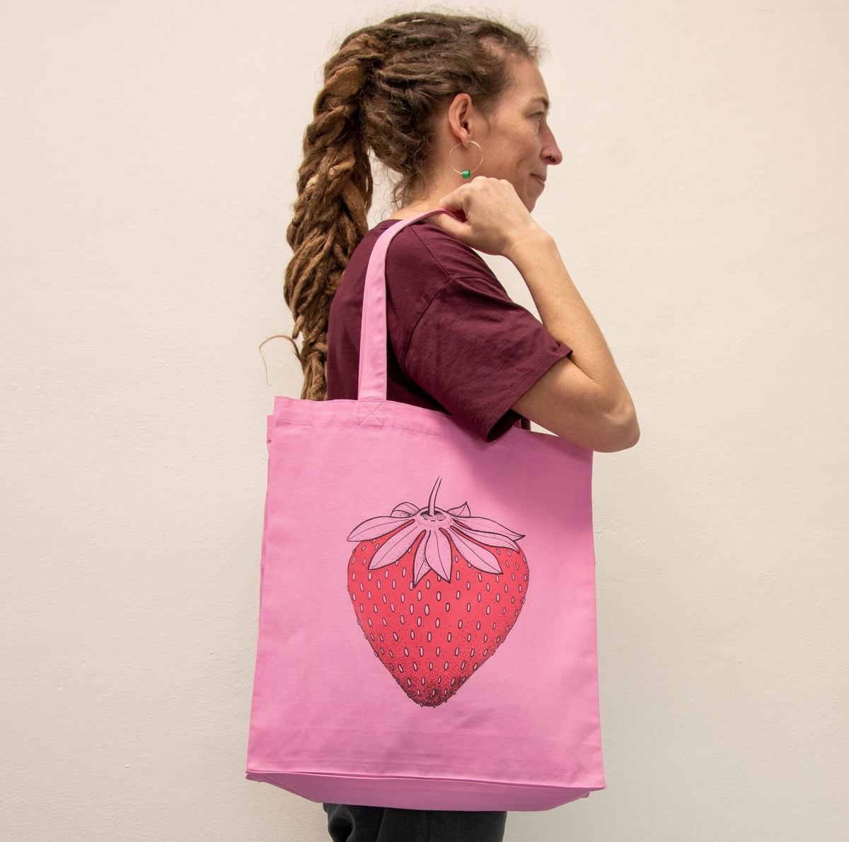 Erdbeer shopper in Bubble Pink getragen von einer Frau. Der farbenfrohe Shopper mit Beeren-Motiv zeigt sich als praktischer Alltagsbegleiter und kreatives Geschenk für Frauen.