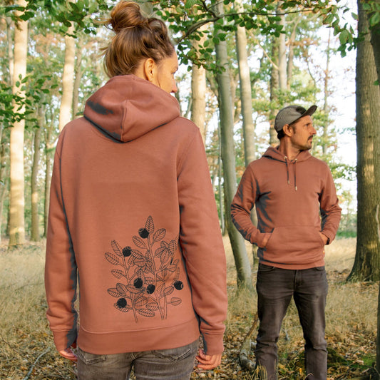 Blaubeere Pullover im Unisex-Schnitt in Heritage Braun. Eine Frau zeigt die Rückansicht mit dem detailreichen Blaubeer-Backprint, während daneben ein Mann die Vorderseite des Bio-Hoodies trägt.
