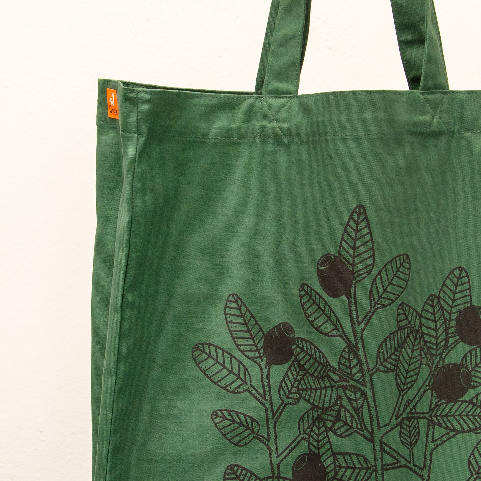 Botanisches Blaubeere-Motiv als Siebdruck auf einer dunkelgrünen Stofftasche. Detailaufnahme der kunstvollen Beeren-Illustration, gefertigt mit umweltfreundlichen, wasserbasierten Textildruckfarben.
