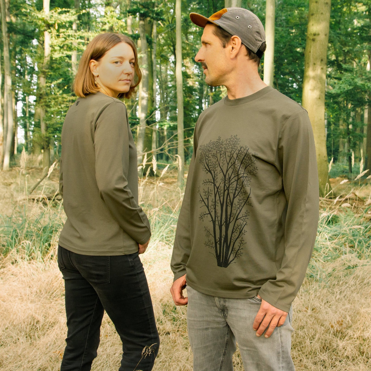 Langarmshirt Baum Design handbedruckt im eigenen Atelier in Hannover. Ein Mann und eine Frau präsentieren das khaki Bio-Sweatshirt mit dem gut sichtbaren Frontprint.
