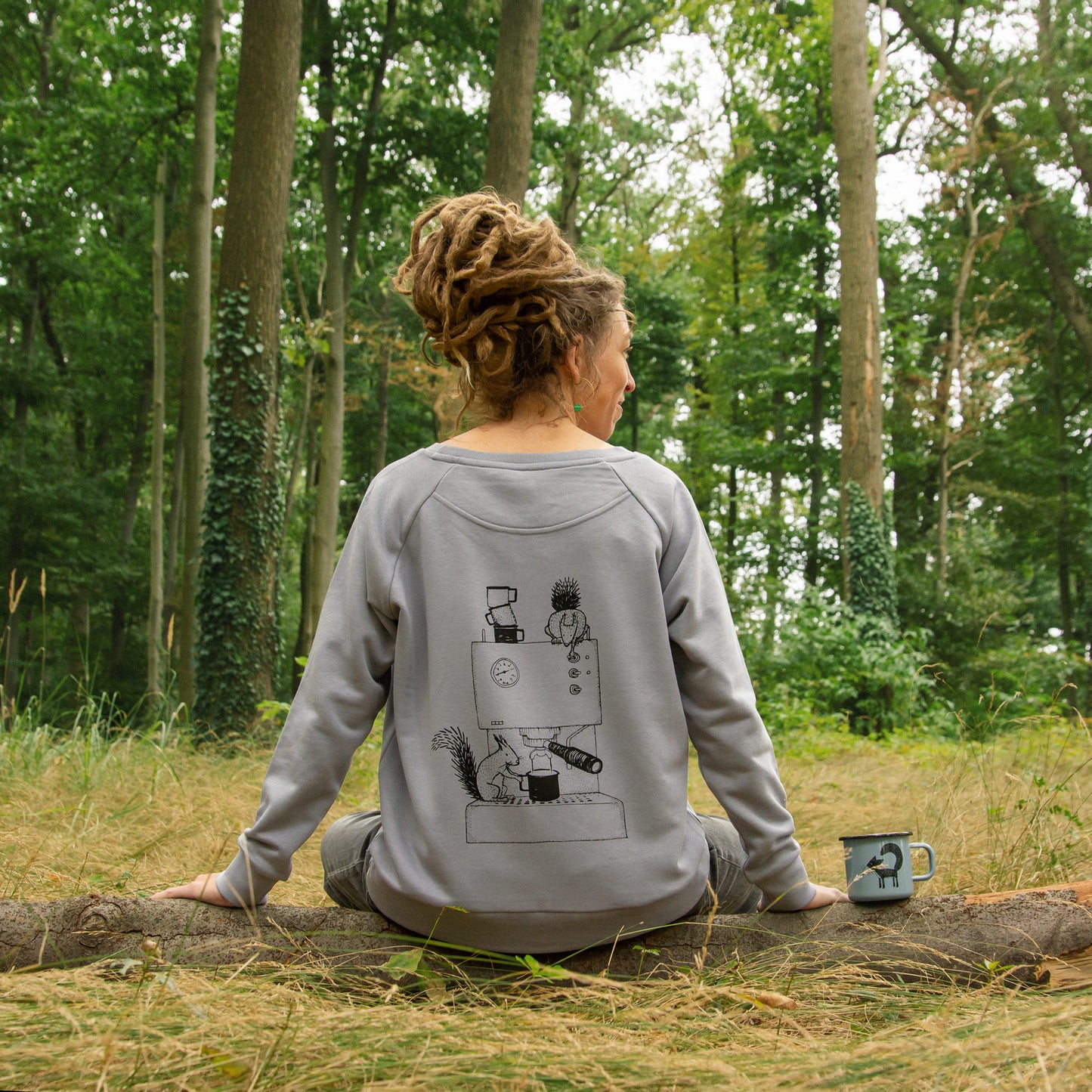 Frau trägt im Wald einen grauen Kaffee Pullover mit Espresso-Motiv und Eichhörnchen auf dem Rückendruck