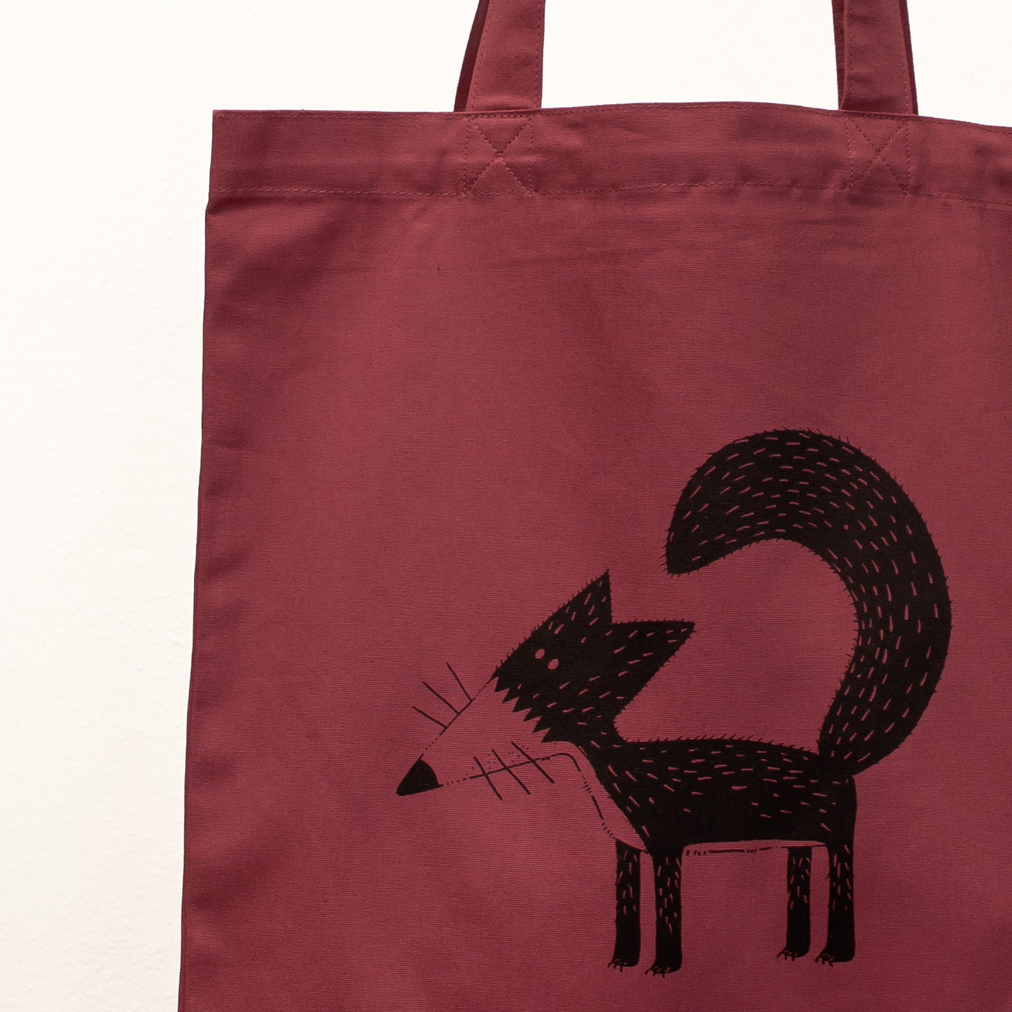 Kunstvolles Fuchs-Motiv als Siebdruck auf einer weinroten Stofftasche. Detailaufnahme der Illustration Franzi, gedruckt mit umweltfreundlichen, wasserbasierten Textildruckfarben.
