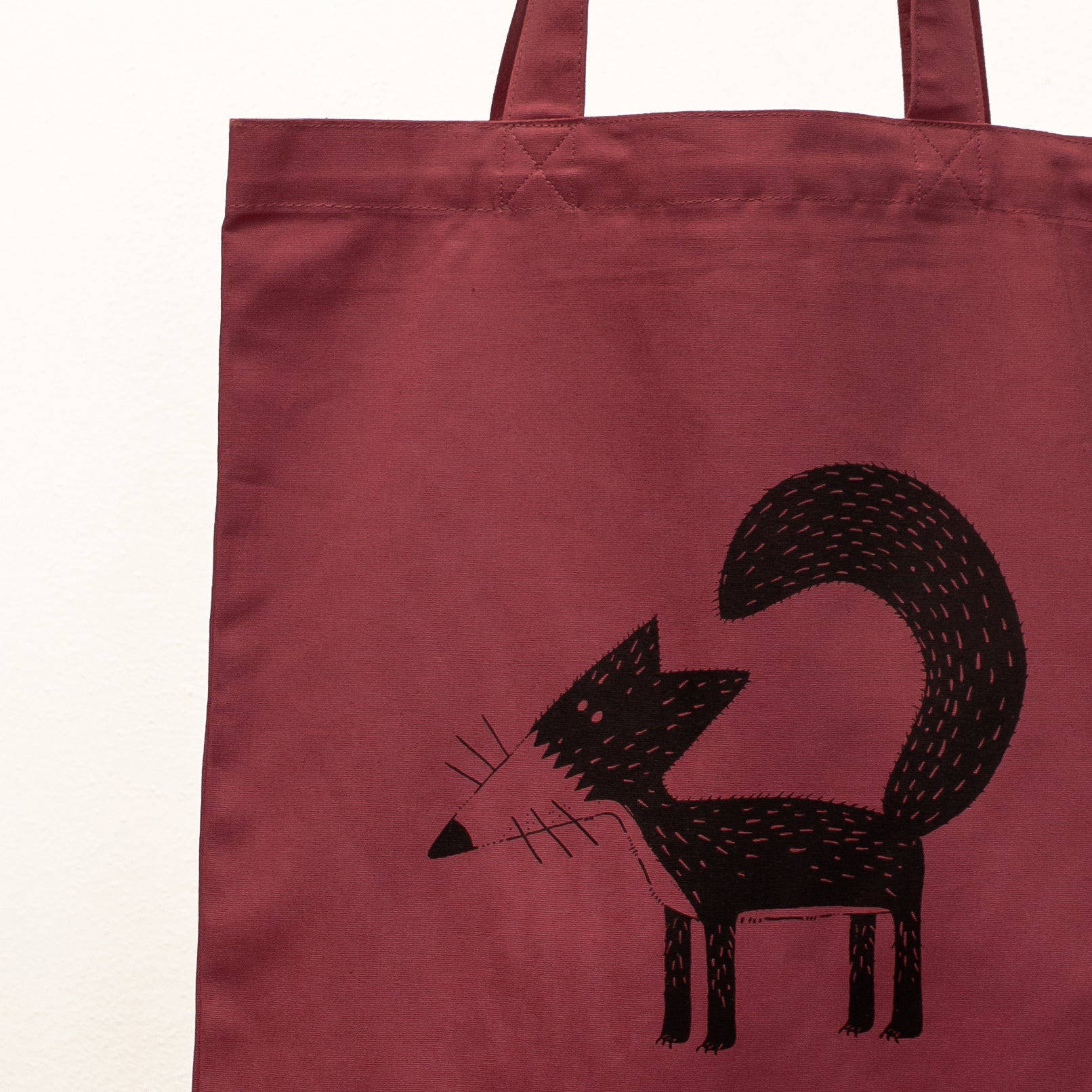 Kunstvolles Fuchs-Motiv als Siebdruck auf einer weinroten Stofftasche. Detailaufnahme der Illustration Franzi, gedruckt mit umweltfreundlichen, wasserbasierten Textildruckfarben.
