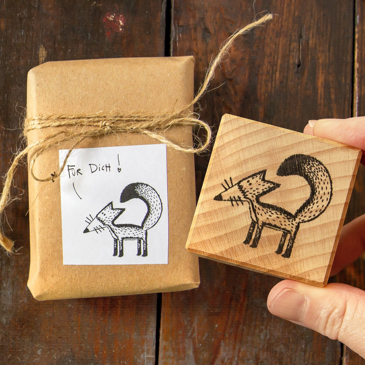 Fuchs Stempel aus Buchenholz für kreative DIY Geschenkverpackungen. Ein Holzstempel liegt neben einem Geschenk, dessen Anhänger-Etikett mit dem Fuchs-Motiv bedruckt ist.
