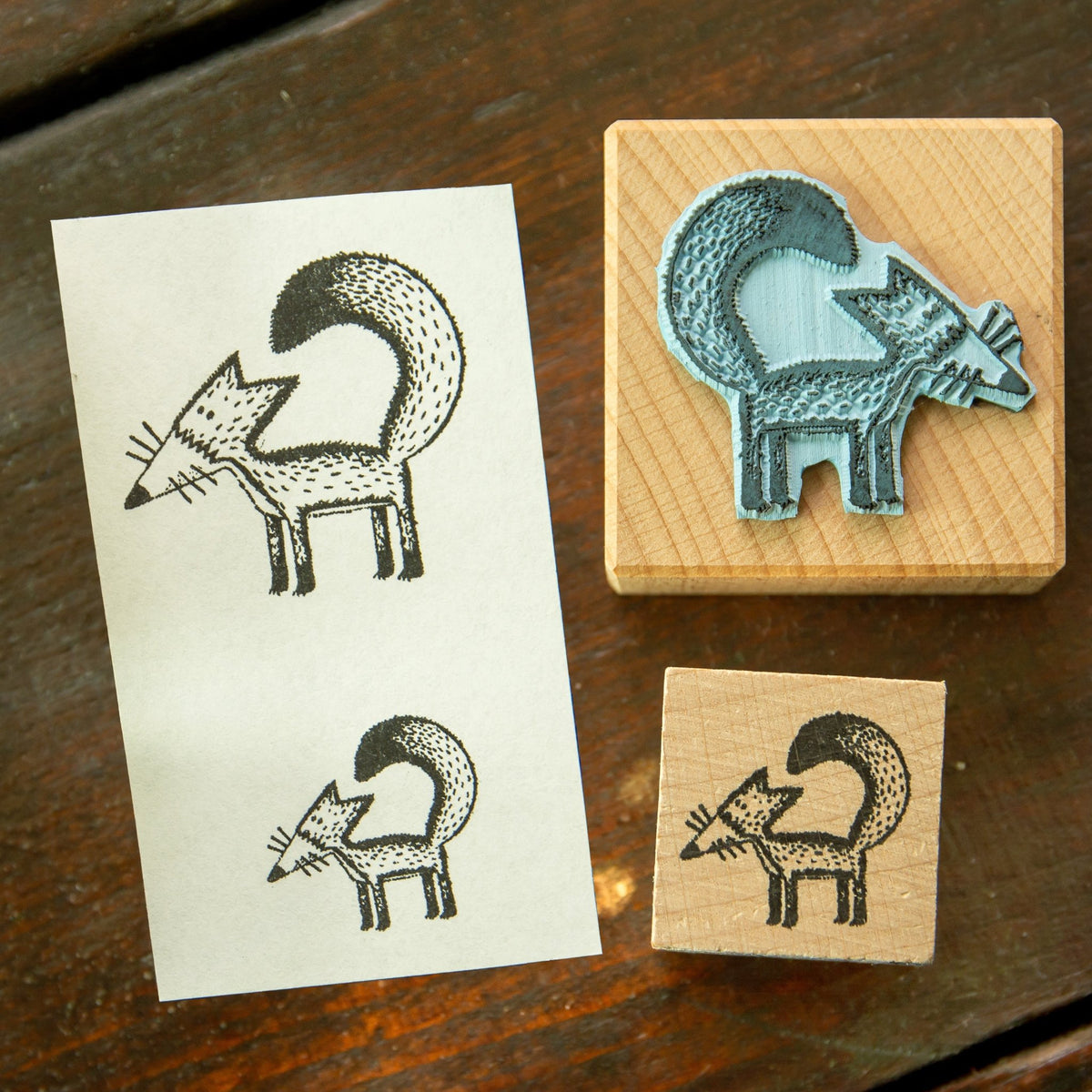Fuchs Stempel Motiv-Abdruck auf Papier. Die Buchenholz-Stempel liegen neben einem Papier, das den sauberen, detaillierten Abdruck des Fuchs-Motivs als Bastel-Inspiration zeigt.
