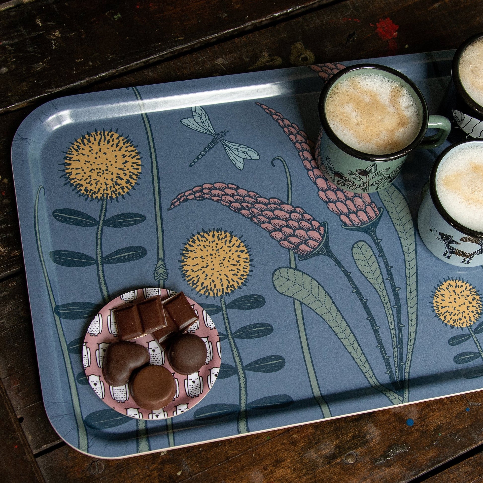 Serviertablett im Scandi-Style aus Birkenfurnier mit botanischem Print. Detailansicht des blau-lila Waldwiesen-Tabletts (53x32 cm), gemütlich angerichtet mit Kaffeetassen und feiner Schokolade.