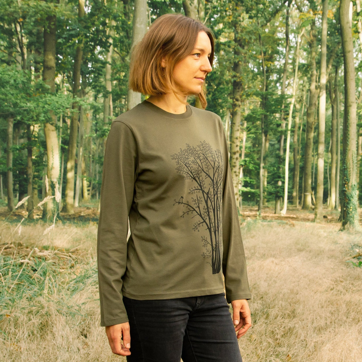 Tshirt Langarm Baum für Damen im lässigen Alltags-Look. Eine Frau trägt das khaki farbene Bio-Baumwoll-Shirt mit dem botanischen Pflanzen-Motiv in einer klaren Vorderansicht.
