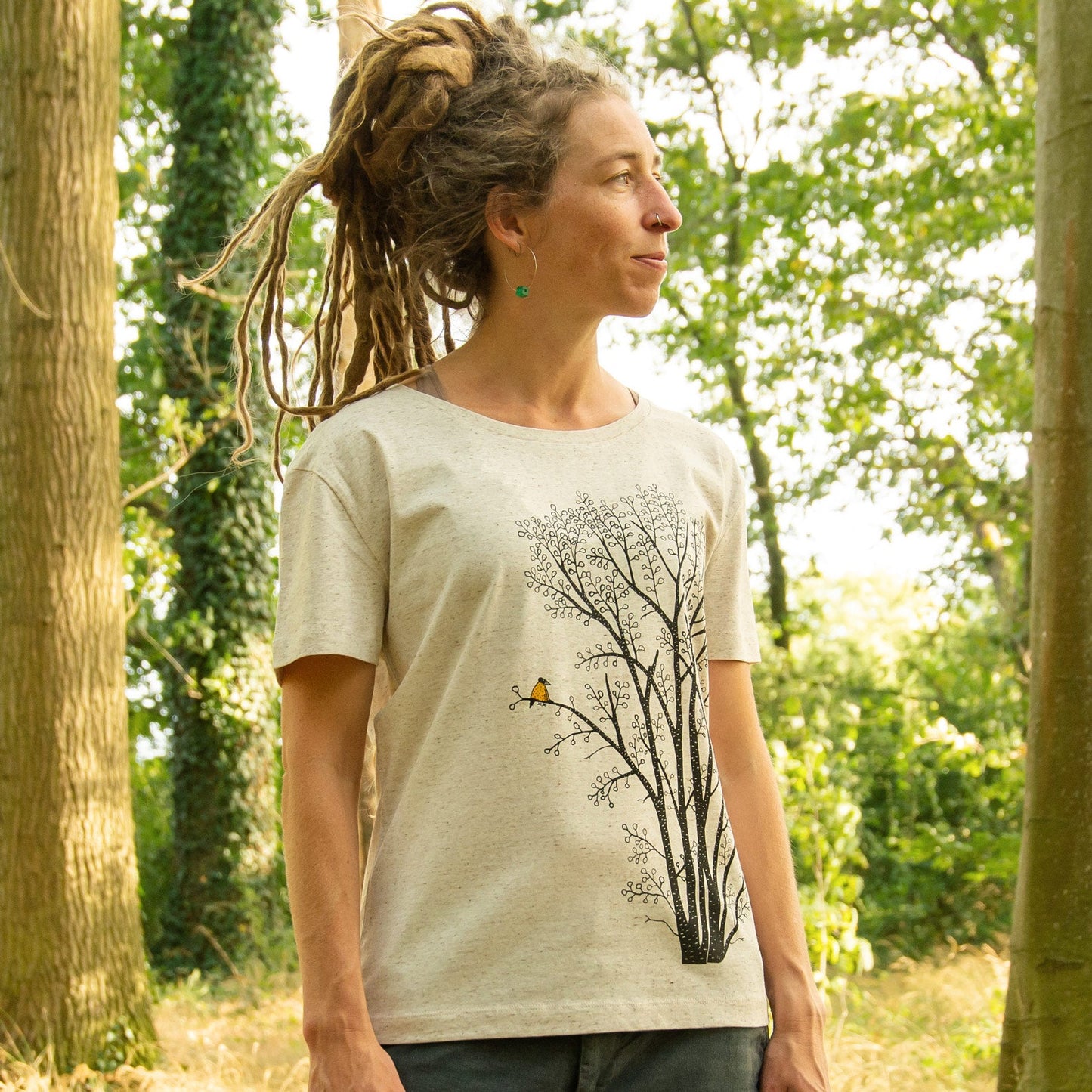 Damen Bio-T-Shirt mit großem Baum-Motiv, Erle und Elster, getragen von einem Model im Wald