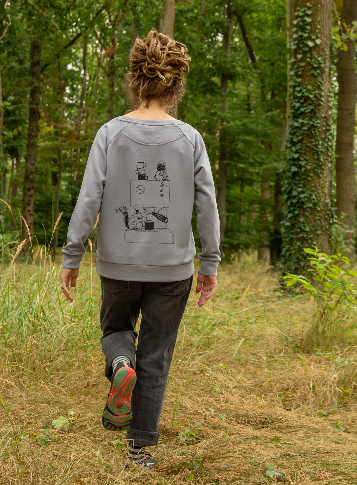 Frau spaziert im Wald mit Kaffee Pullover und Eichhörnchen Espresso Rückendruck
