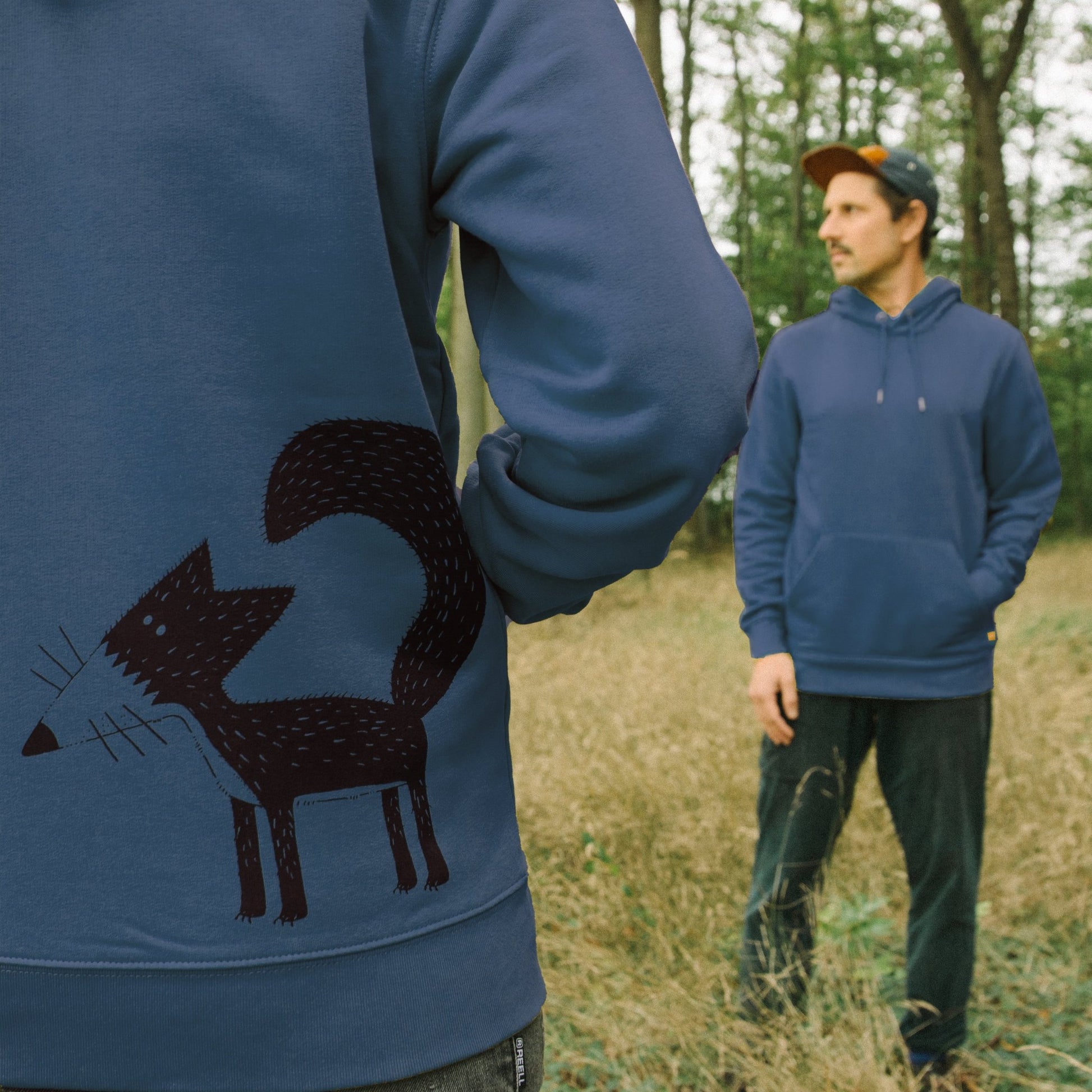Fuchs Hoodie mit dem detailreichen Franzi-Fuchs-Backprint im Vordergrund. Die Nahaufnahme zeigt die hohe Qualität des Siebdrucks auf dem dunkel-blaugrünen Dark Teal Stoff.
