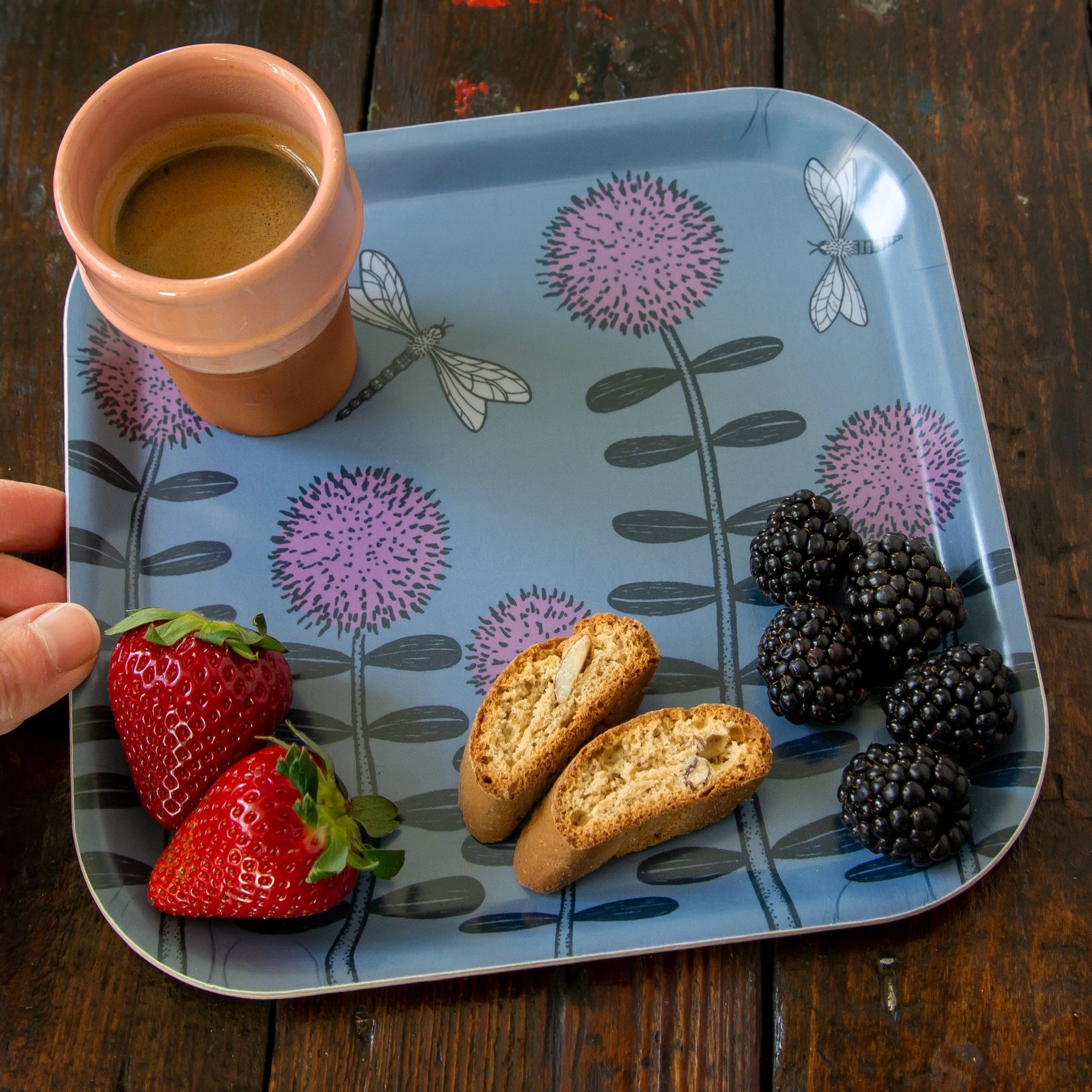 Schwedisches Design Kaffee-Tablett aus Holz mit Espresso und Beeren. Kleines quadratisches Serviertablett in Blau-Grau mit Blumenwiese, gemütlich gedeckt mit einer Tasse Espresso, italienischem Mandelgebäck, roten Erdbeeren und Brombeeren.