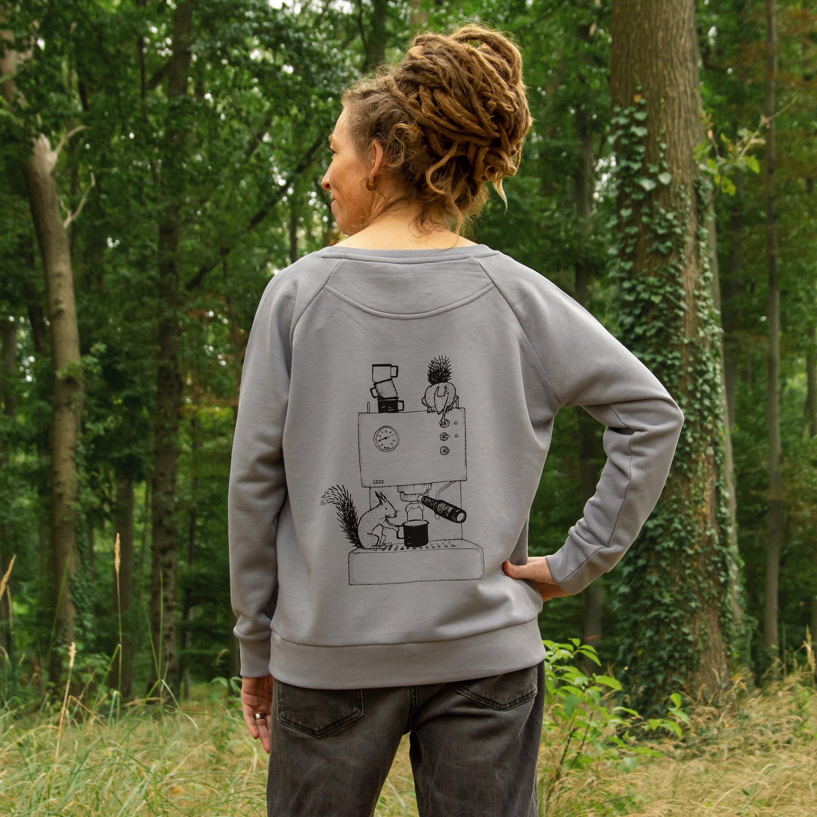 Frau im Wald von hinten mit grauem Kaffee Pullover und Espresso Motiv auf dem Rücken