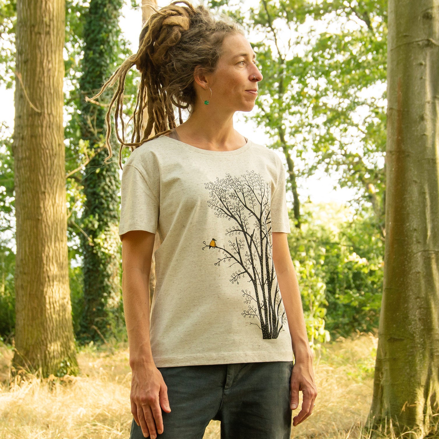 Damen Bio-T-Shirt mit großem Baum-Motiv, Erle und Elster, getragen von einem Model im Wald