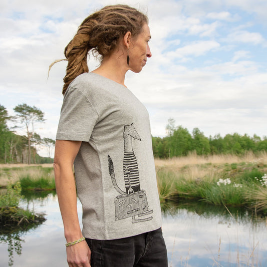 Wiesel T-Shirt für Damen im lässigen Alltags- und Reise-Look. Eine Frau präsentiert die klassische Vorderansicht des grau melierten Bio-Shirts mit dem Urlaub-Motiv im Freien.
