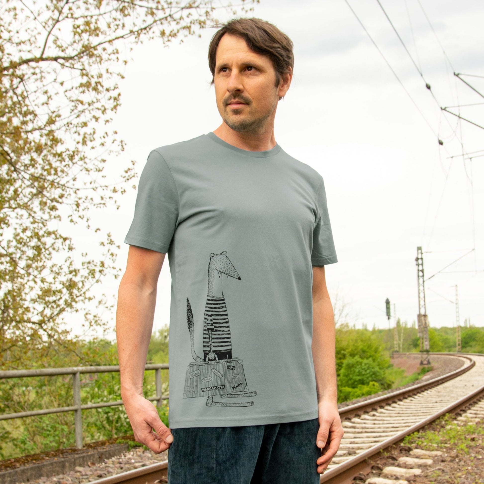 Wiesel T-Shirt für Herren als kreative Geschenkidee für Reise-Fans. Ein Mann präsentiert die Vorderansicht des hellgrauen Misty Grey Bio-Shirts mit dem lustigen Urlaubs-Motiv von vorne.
