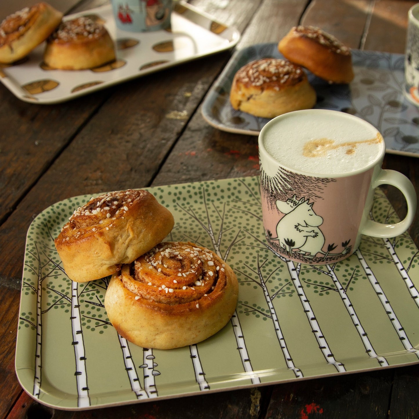 Kaffee-Tablett im Scandi-Style aus Birkenfurnier mit skandinavischer Tasse. Kleines grünes Serviertablett aus schwedischer Produktion, gedeckt mit einer schwedischen Zimtschnecke und der Mumintasse Liebe voller Kaffee für die Fika-Pause.