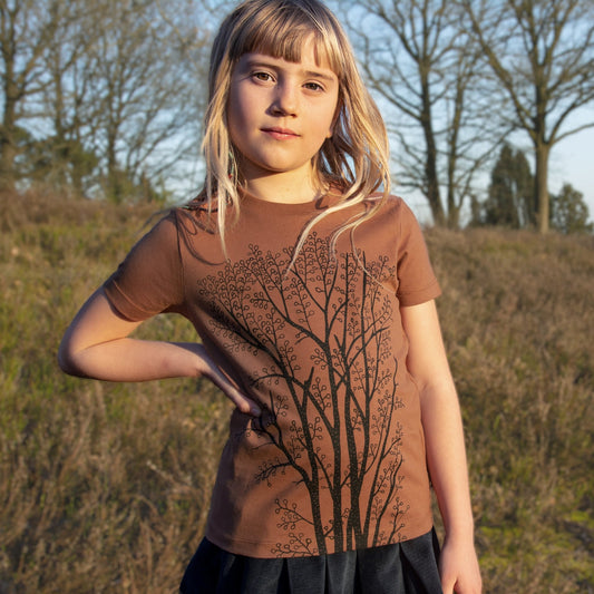 Kinder Tshirt Baum Motiv für Mädchen in der herbstlichen Farbe Braun. Ein kleines Mädchen trägt das handbedruckte Bio-T-Shirt mit dem großen Erlenbaum-Frontprint von vorne.
